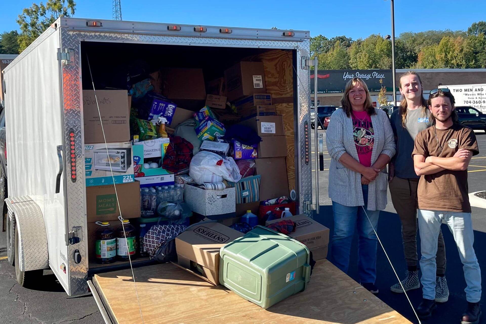 Volunteers of all ages standing beside a packed trailer