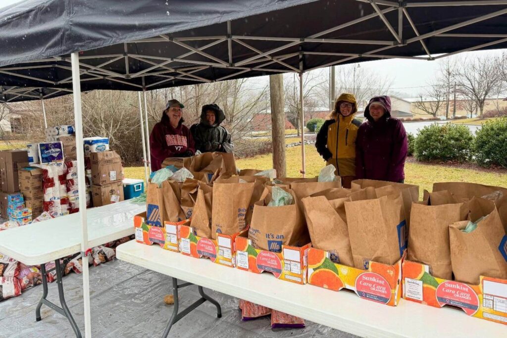 Women standing under a tent with filled grocery bags