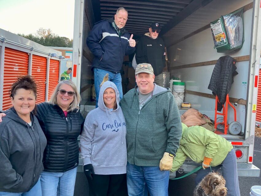 Men and women standing in back of covered truck