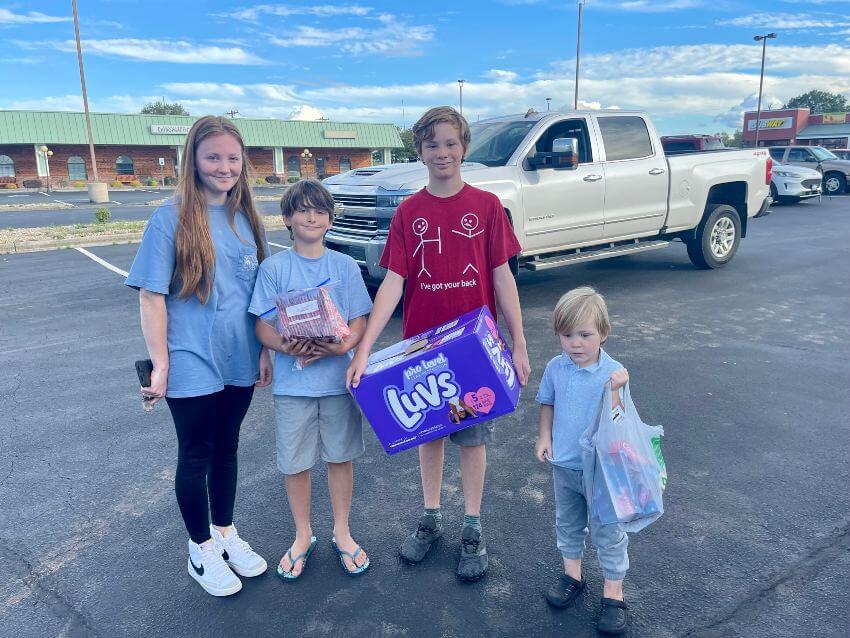 Four children in parking lot with donations bags