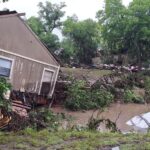 House destroyed laying sideways in a river