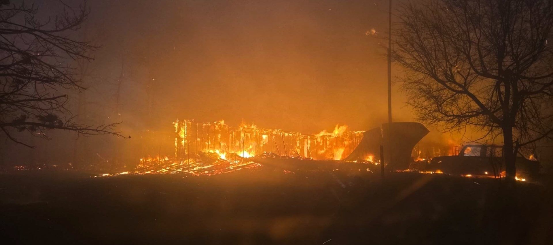 view from car window of a house, car, and land on fire